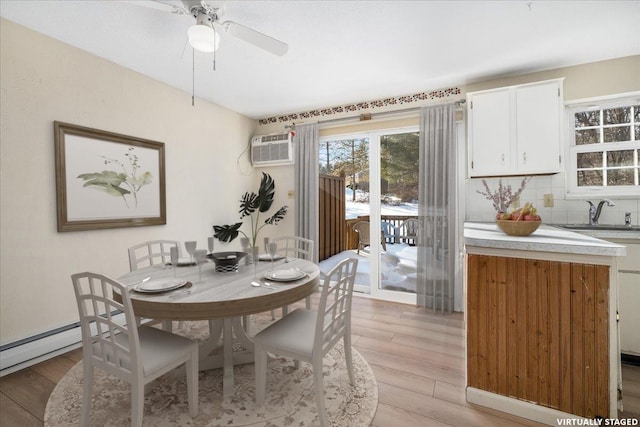 dining room featuring ceiling fan, a wall mounted AC, and light wood-type flooring