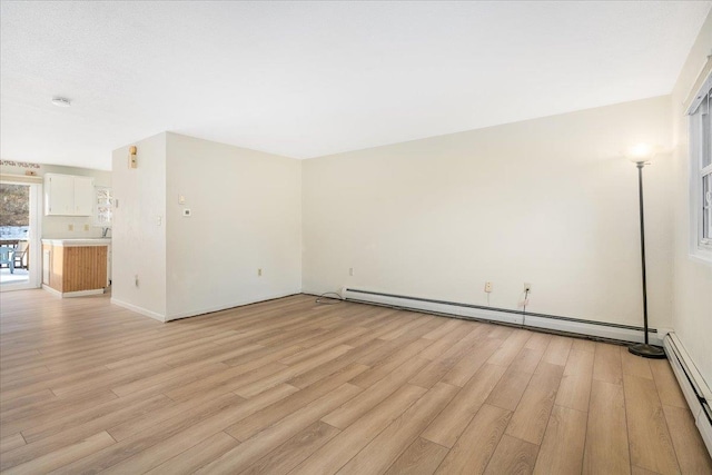 unfurnished living room with a baseboard heating unit, light wood-type flooring, and baseboards