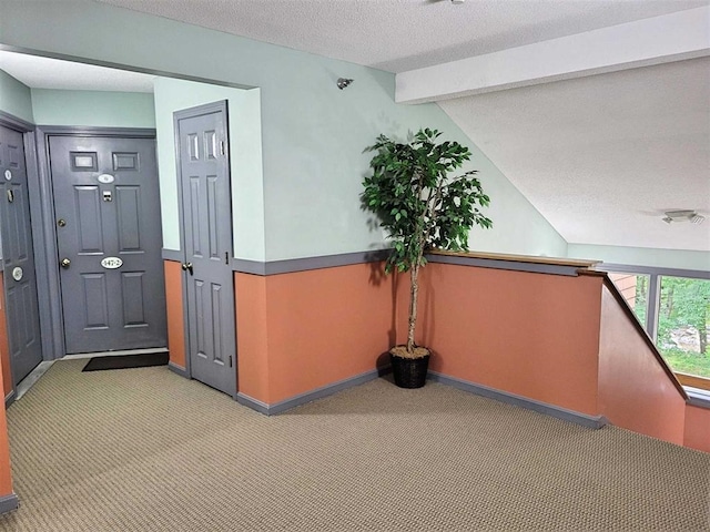 interior space with a textured ceiling, lofted ceiling with beams, and baseboards