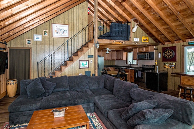 living area featuring stairway, wood finished floors, wood walls, and high vaulted ceiling