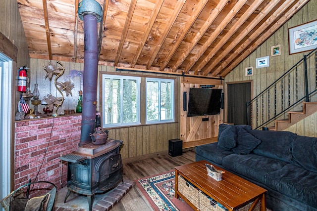 living area with stairway, a wood stove, lofted ceiling, and wood finished floors