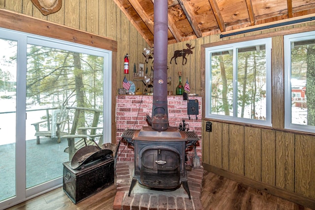 interior space with wood walls, a fire extinguisher, a wood stove, and wood finished floors