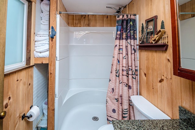 full bath with a shower with shower curtain, toilet, and wooden walls