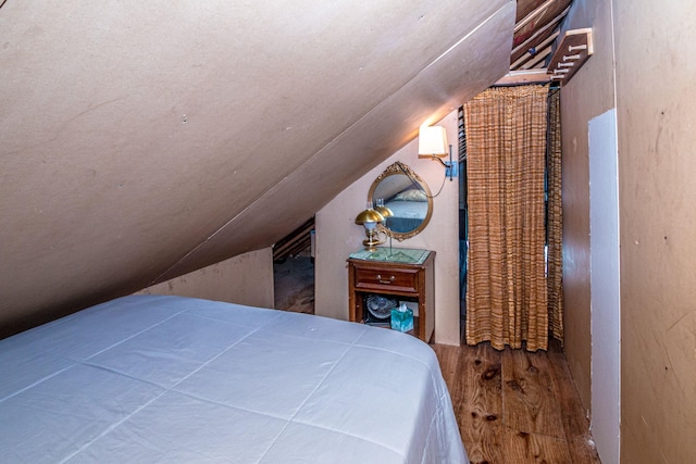 bedroom with lofted ceiling and wood finished floors