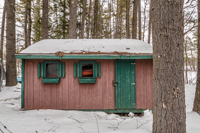 snow covered structure featuring an outbuilding