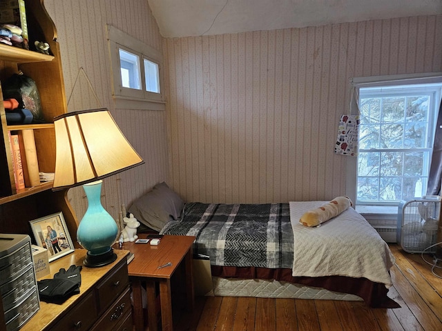 bedroom featuring lofted ceiling, hardwood / wood-style flooring, and wallpapered walls