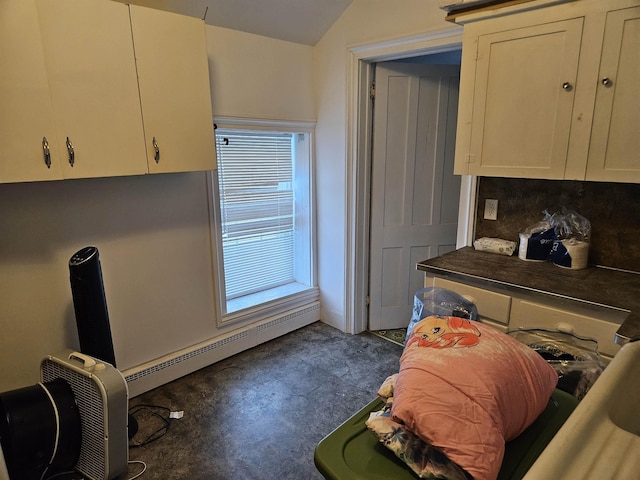 kitchen featuring a baseboard radiator, vaulted ceiling, and white cabinets