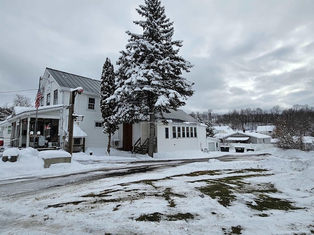 view of snowy exterior featuring a standing seam roof and metal roof