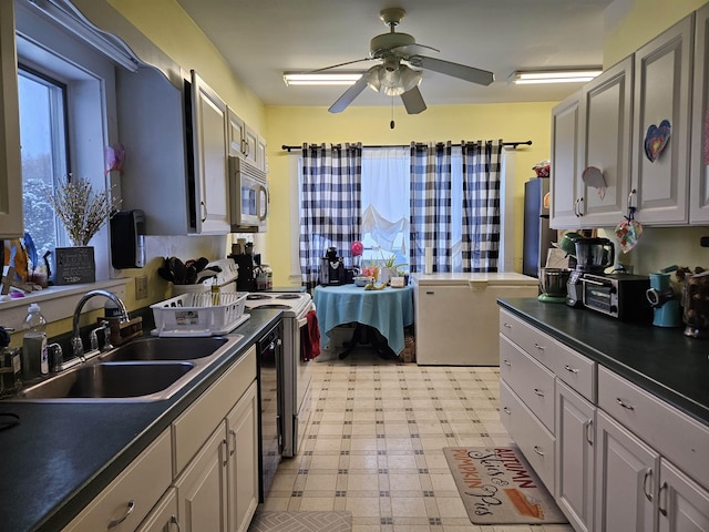 kitchen featuring dark countertops, light floors, stainless steel microwave, and a sink