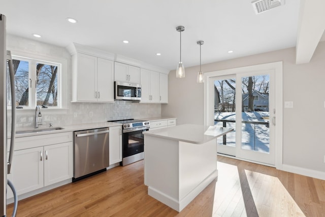 kitchen with stainless steel appliances, light countertops, visible vents, and a sink