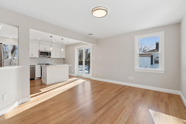 unfurnished living room featuring light wood-type flooring, visible vents, baseboards, and recessed lighting