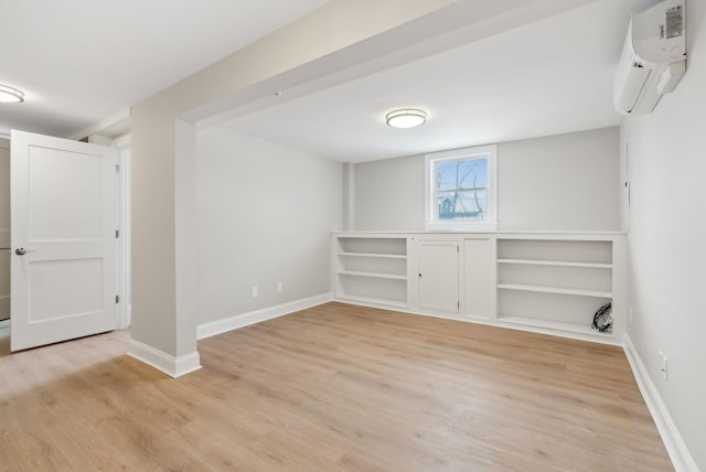 below grade area featuring a wall unit AC, light wood-style flooring, and baseboards