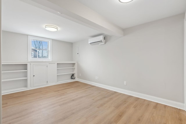 interior space with light wood-type flooring, a wall unit AC, and baseboards