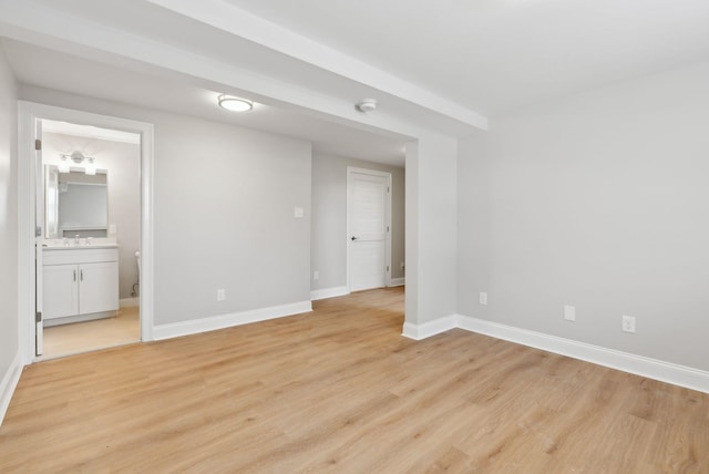 spare room with light wood finished floors, baseboards, and a sink