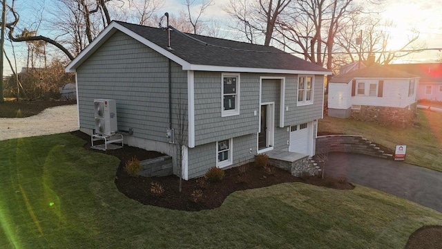 view of front facade with a garage, aphalt driveway, a shingled roof, and a front yard