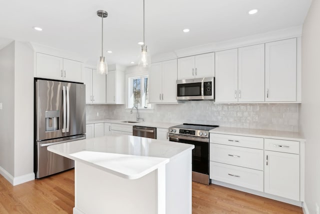 kitchen with decorative backsplash, appliances with stainless steel finishes, light wood-style floors, white cabinetry, and a sink