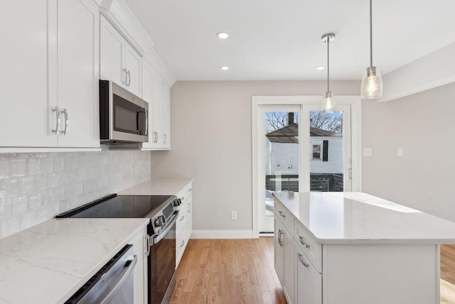 kitchen featuring a center island, stainless steel appliances, light wood-type flooring, white cabinetry, and backsplash