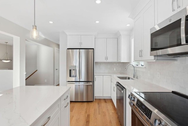 kitchen featuring white cabinetry, appliances with stainless steel finishes, light stone counters, and a sink