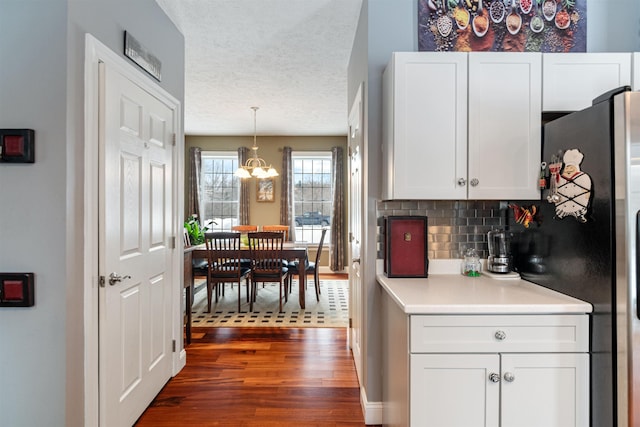 kitchen with light countertops, dark wood-style flooring, white cabinets, and backsplash