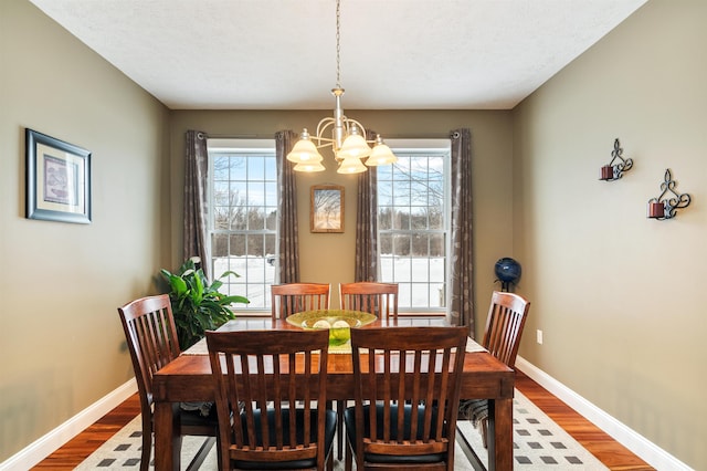 dining space with an inviting chandelier, baseboards, and wood finished floors