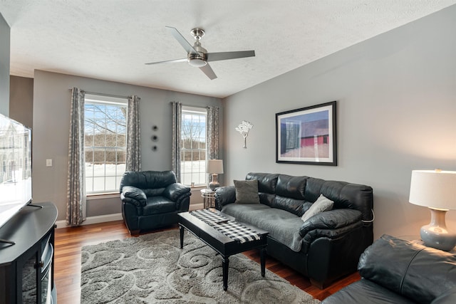 living room with a ceiling fan, a textured ceiling, baseboards, and wood finished floors