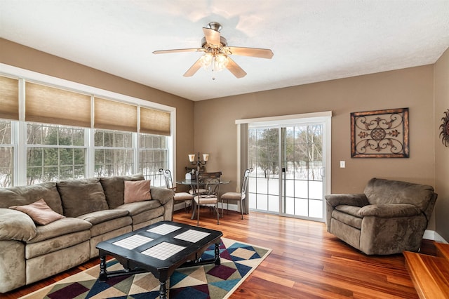 living area with wood finished floors, a ceiling fan, and baseboards