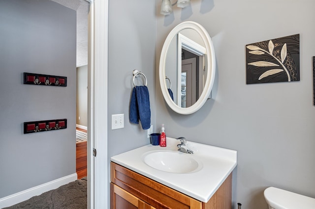 bathroom with vanity, toilet, and baseboards