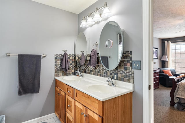 bathroom featuring baseboards, double vanity, a sink, and decorative backsplash