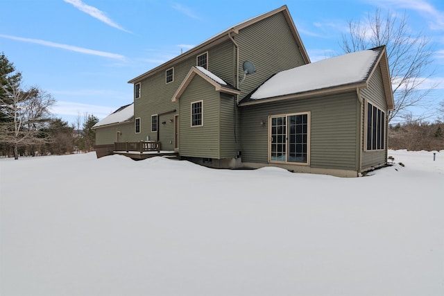 snow covered back of property with a deck