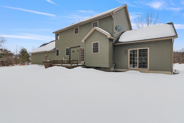 snow covered back of property with a wooden deck