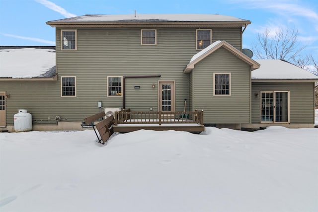 snow covered back of property featuring a deck