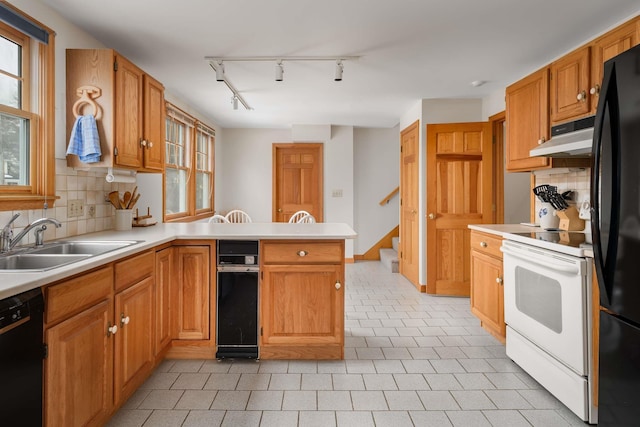 kitchen featuring decorative backsplash, a peninsula, under cabinet range hood, black appliances, and a sink