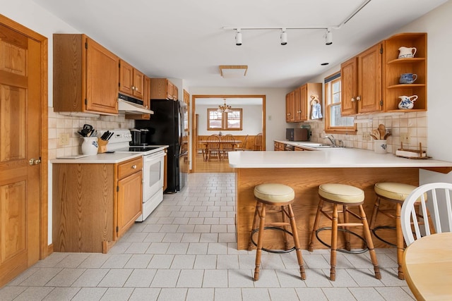 kitchen featuring light countertops, a wealth of natural light, white electric range oven, and under cabinet range hood