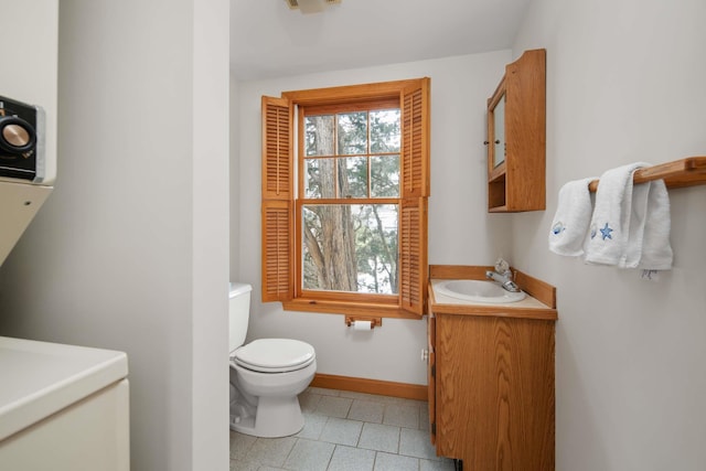 bathroom with tile patterned flooring, vanity, toilet, and baseboards