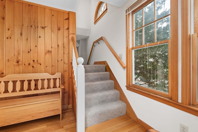 stairway with wood finished floors and wooden walls