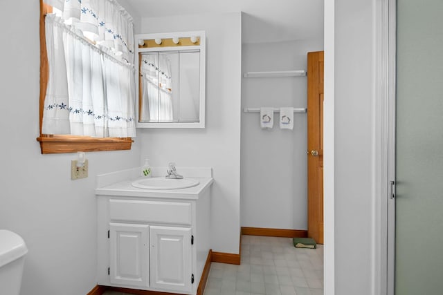 bathroom featuring toilet, vanity, and baseboards