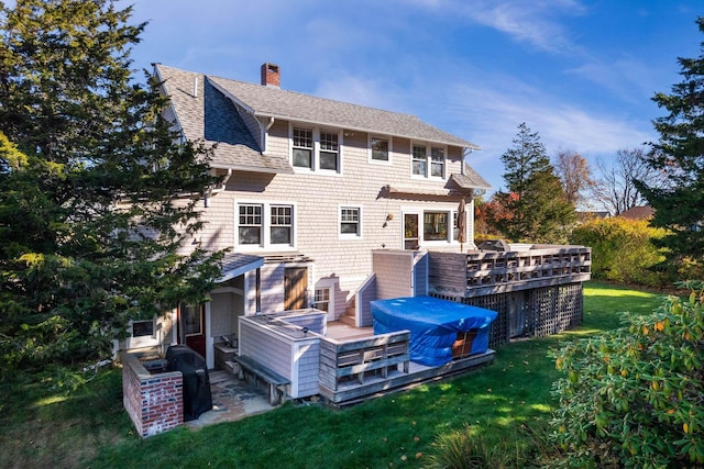 rear view of house with a chimney, roof with shingles, a yard, and a deck