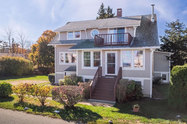 shingle-style home featuring a balcony, a shingled roof, and a chimney