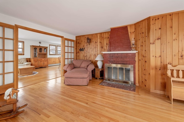 living room with wooden walls, a baseboard radiator, a fireplace, and wood finished floors