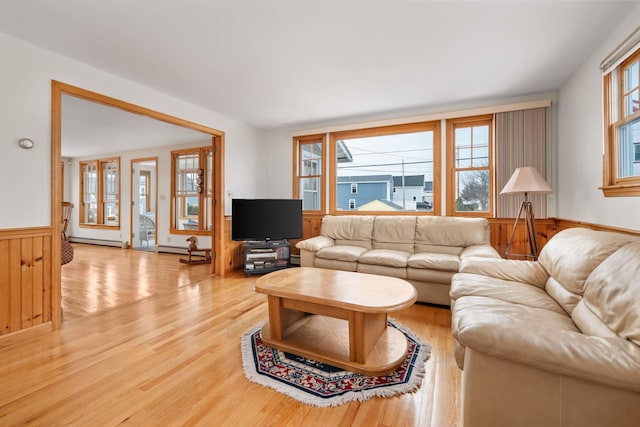 living room with light wood finished floors, a baseboard radiator, and a wainscoted wall