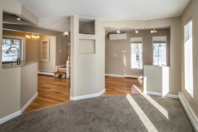 hall featuring light colored carpet, a wall mounted air conditioner, baseboard heating, a baseboard heating unit, and a sink