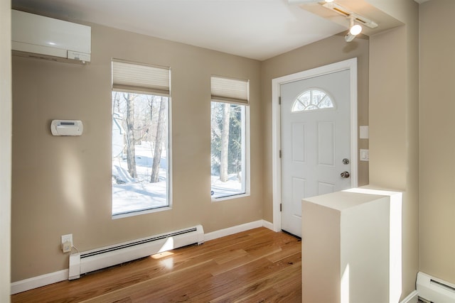 foyer entrance featuring baseboards, a baseboard radiator, wood finished floors, an AC wall unit, and a baseboard heating unit