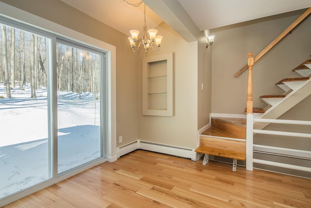 doorway featuring light wood-style flooring, baseboards, stairs, baseboard heating, and an inviting chandelier