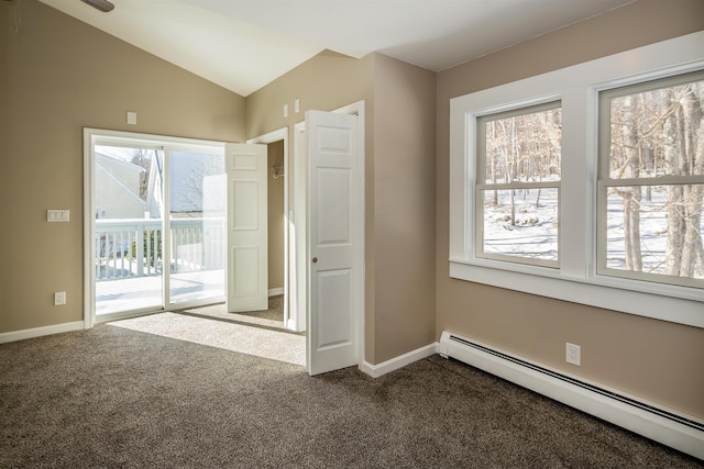 carpeted empty room featuring a baseboard heating unit, vaulted ceiling, and baseboards