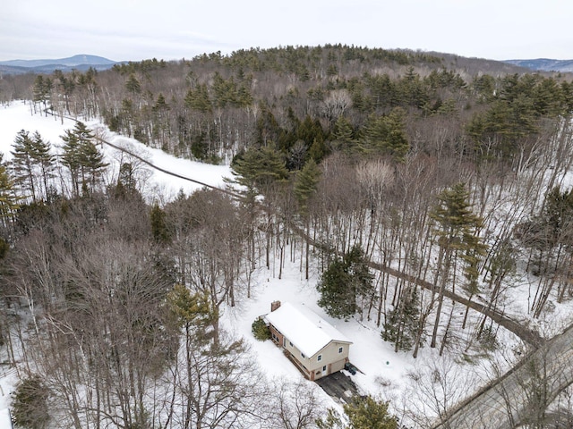 snowy aerial view with a mountain view and a forest view