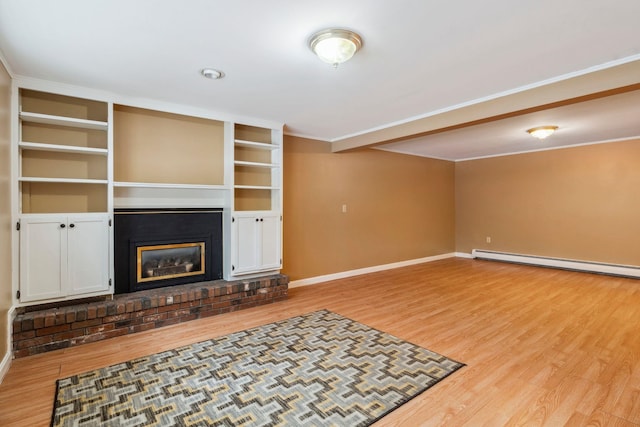 unfurnished living room with a baseboard heating unit, baseboards, ornamental molding, light wood-type flooring, and a glass covered fireplace