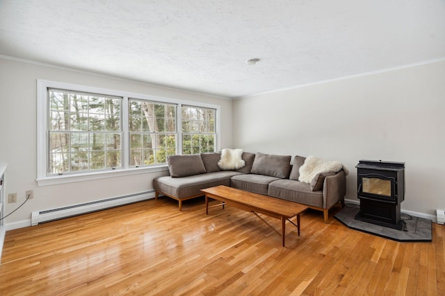 living area featuring a wood stove, light wood-style flooring, ornamental molding, and baseboard heating