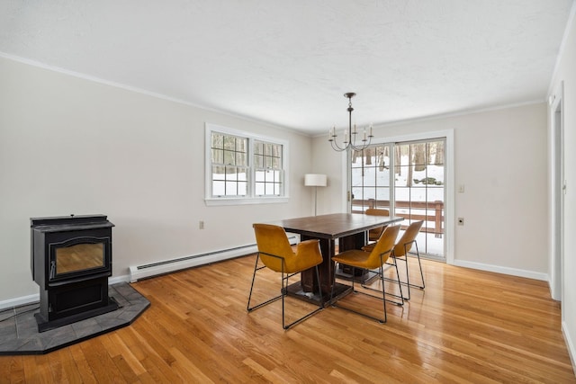 dining room with ornamental molding, light wood-type flooring, a wood stove, and baseboard heating