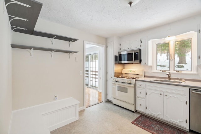 kitchen featuring a textured ceiling, appliances with stainless steel finishes, white cabinets, and a sink