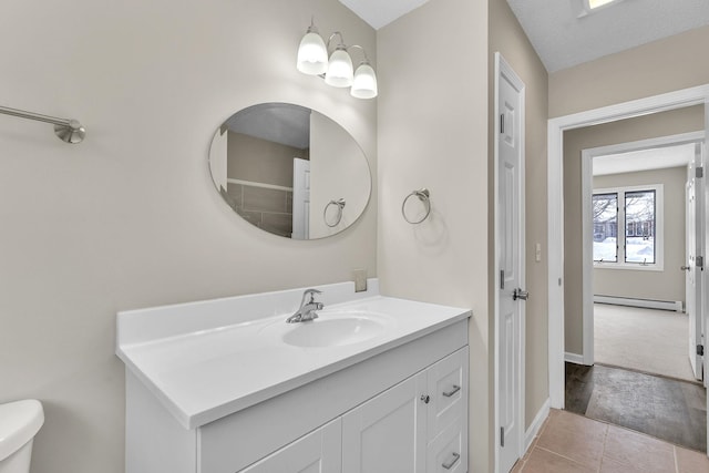 bathroom featuring a baseboard radiator, toilet, vanity, baseboards, and tile patterned floors